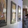 A military service member in Army Combat Uniform (ACU/OCP pattern) wearing a black cavalry Stetson hat gives a thumbs-up gesture in what appears to be a military heritage or museum hallway. The wall displays several framed military unit artwork or guidon prints, including one featuring an eagle emblem consistent with U.S. Army heraldry. The setting appears to be an indoor military facility or historic building.