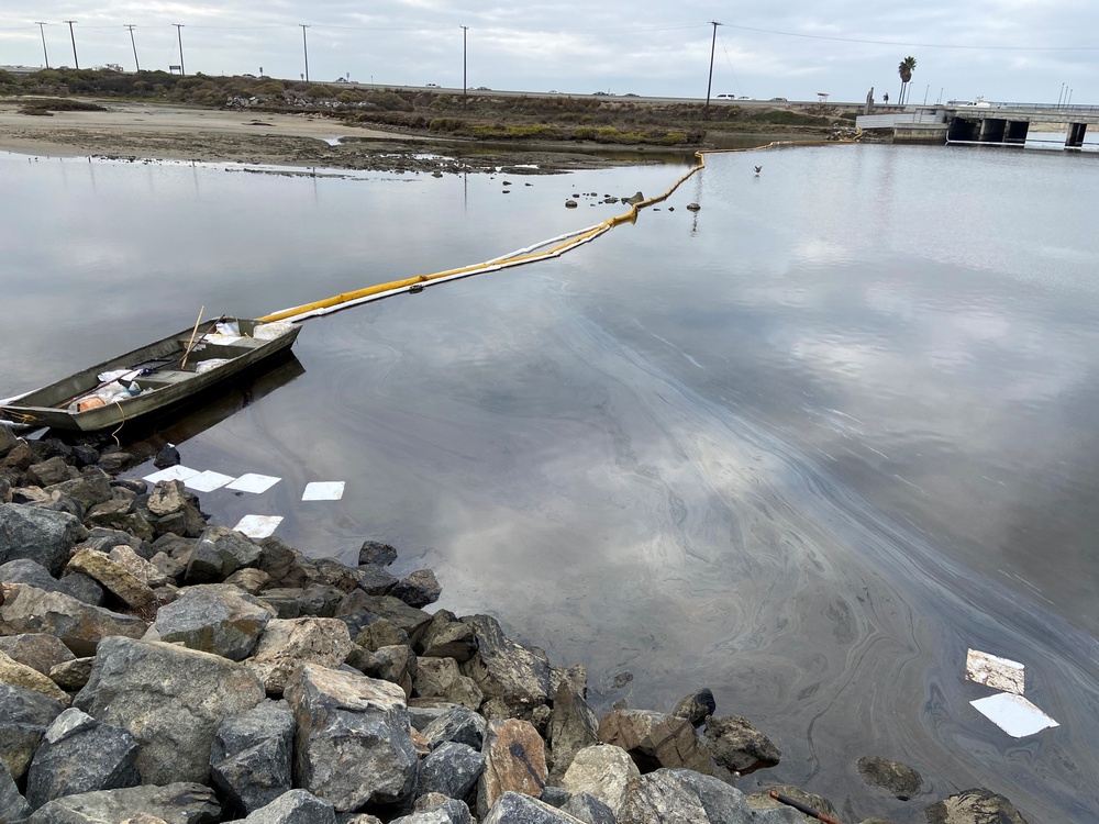 Contractors remove oil near a marsh area in Huntington Beach, California
