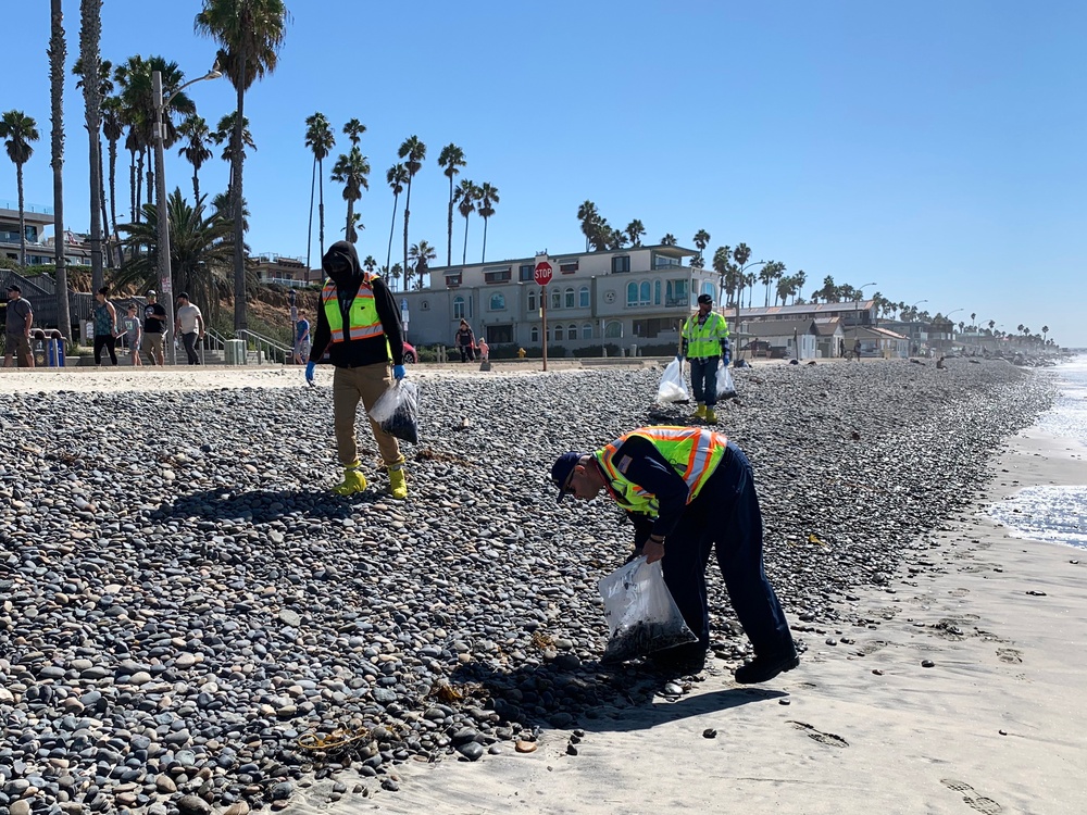 Contractors on a hotshot team to remove tar balls from shores in Oceanside Harbor Beach in San Diego County