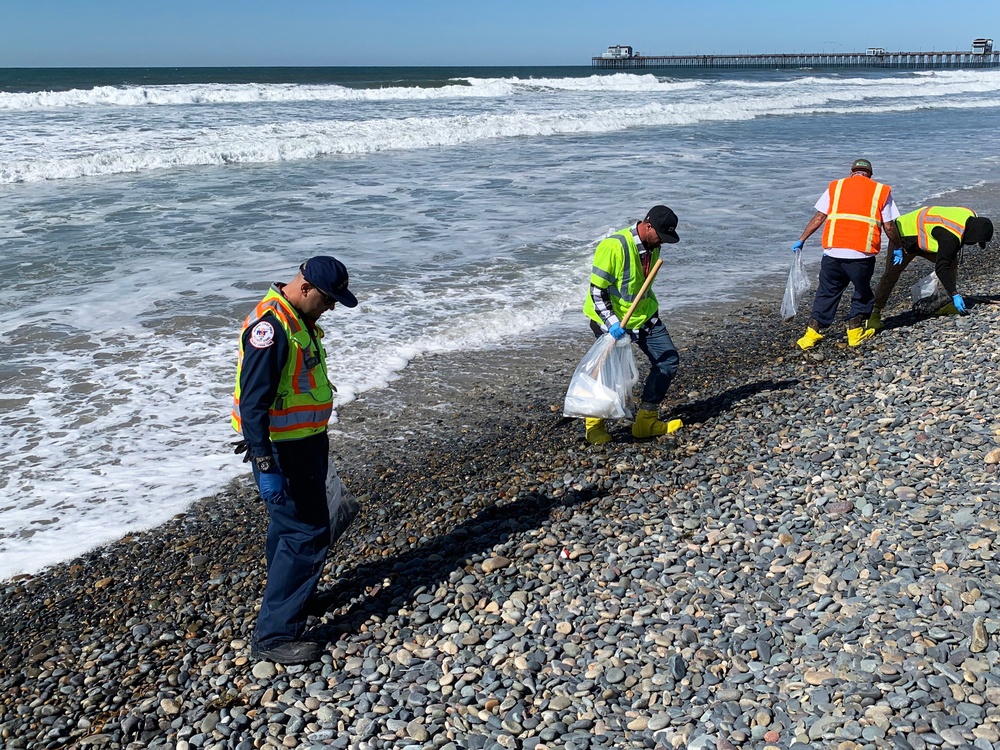 Contractors on a hotshot team to remove tar balls from shores in Oceanside Harbor Beach in San Diego County