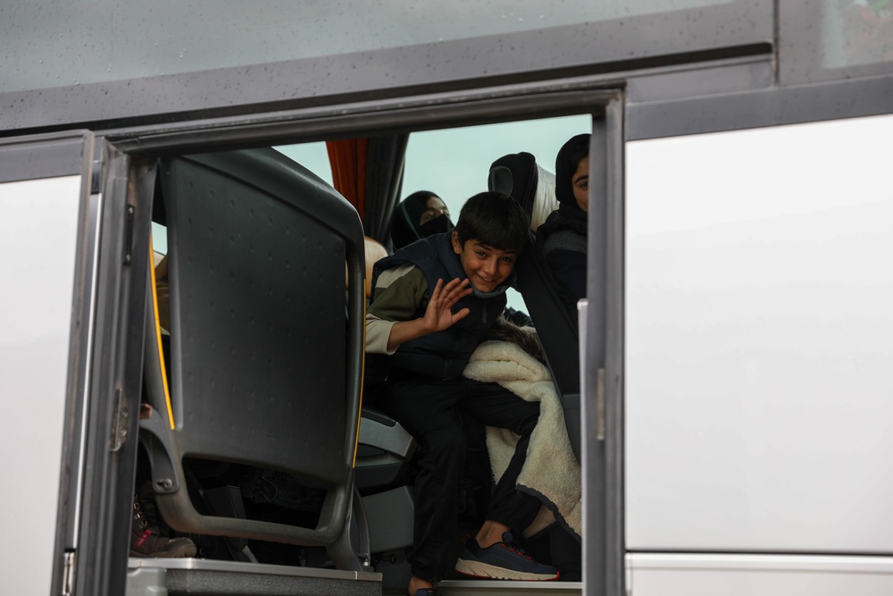 Afghan traveler waves goodbye as they travel onward to United States