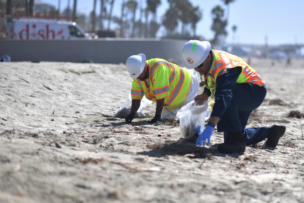 Petty Officer 1st Class Christopher Romero and contracted cleanup teams remove tar balls from the shoreline in Oceanside Harbor