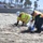 Petty Officer 1st Class Christopher Romero and contracted cleanup teams remove tar balls from the shoreline in Oceanside Harbor