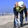 Petty Officer 1st Class Christopher Romero and contracted cleanup teams remove tar balls from the shoreline in Oceanside Harbor