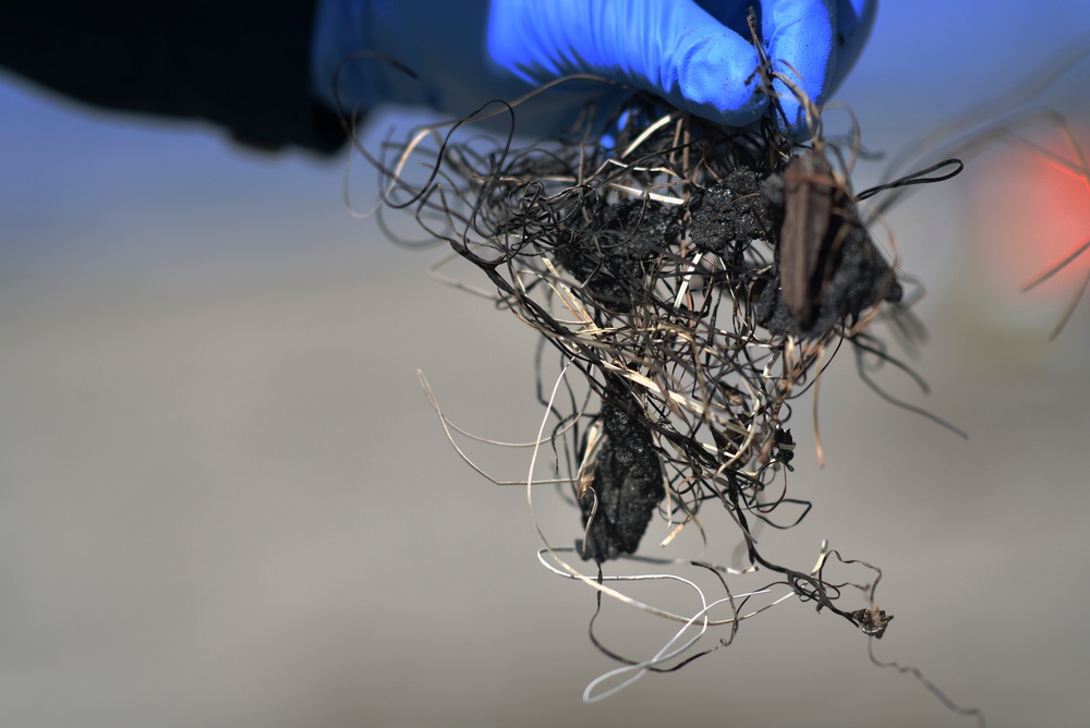 A clean up team member removes a tar ball from the shore of Oceanside Harbor Beach