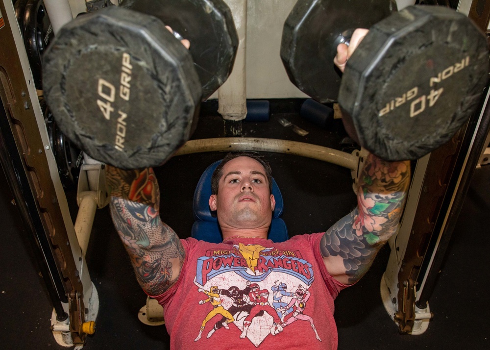 CS1 Bennett Evans Uses Dumbbells for Bench Press during a Physical Training Session