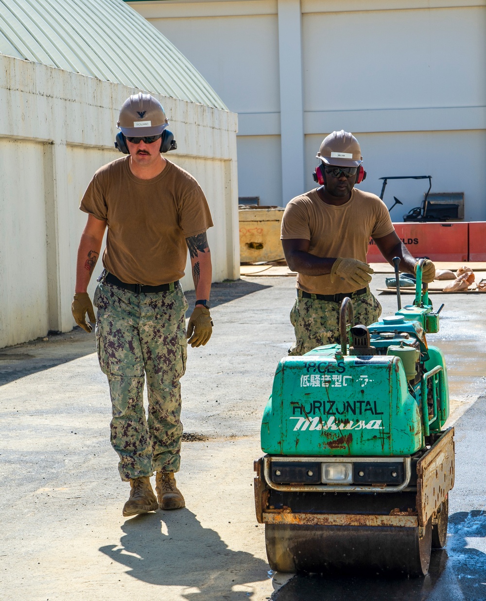 US Navy Seabees assigned to NMCB-5 place asphalt onboard Camp Shields