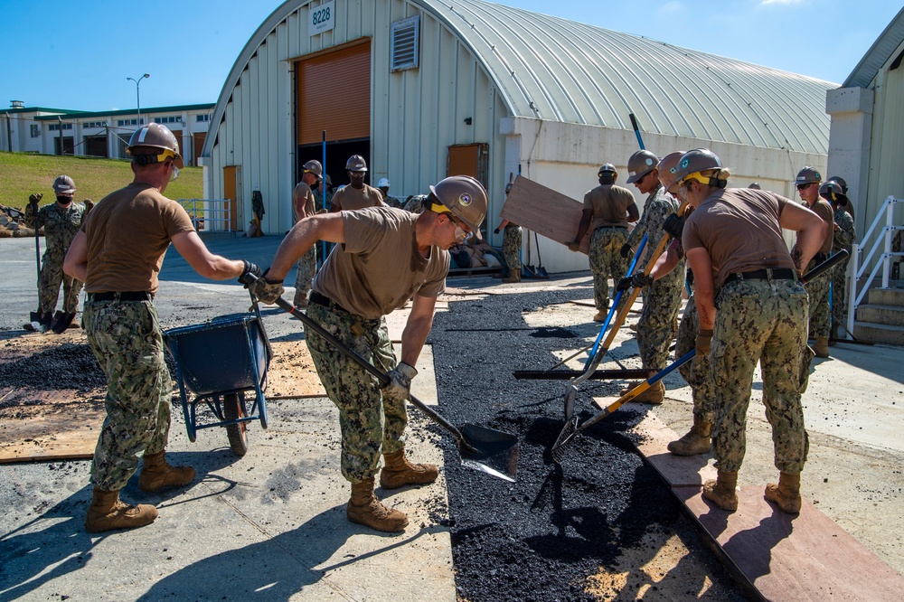 US Navy Seabees assigned to NMCB-5 place asphalt onboard Camp Shields