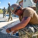 US Navy Seabees assigned to NMCB-5 place asphalt onboard Camp Shields