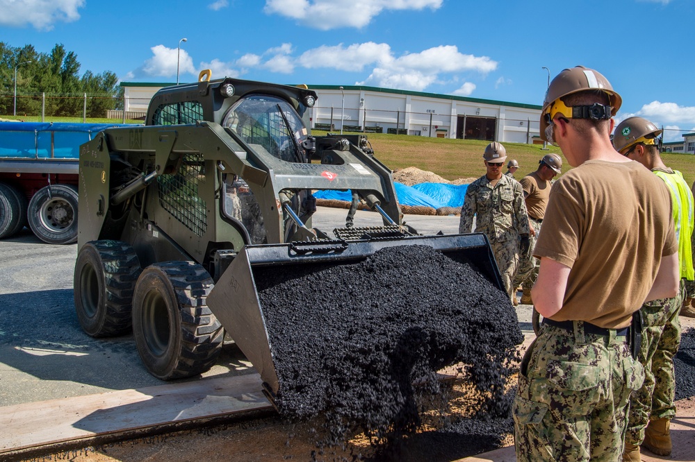 US Navy Seabees assigned to NMCB-5 place asphalt onboard Camp Shields