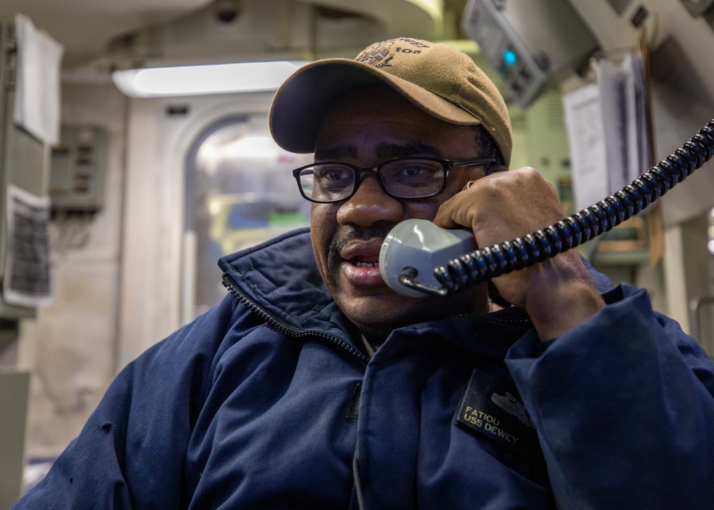 MMC Fatiou Assani Speaks into the Internal Voice Communication System aboard USS Dewey