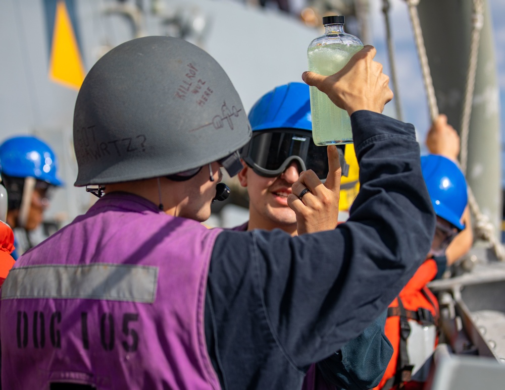 USS Dewey Sailors Inspect a Fuel Sample during a Replenishment-at-sea