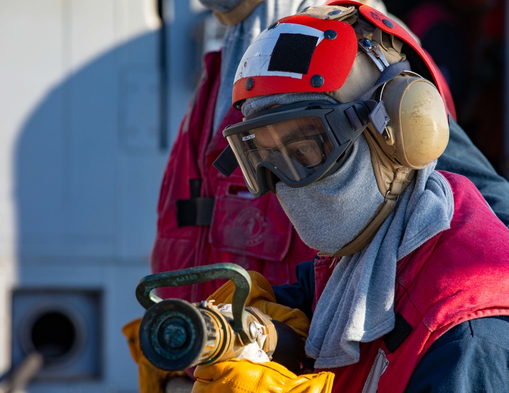 DCFN Vinz Torres Holds an AFFF Hose on the Flight Deck aboard USS Dewey during Crash and Salvage Training