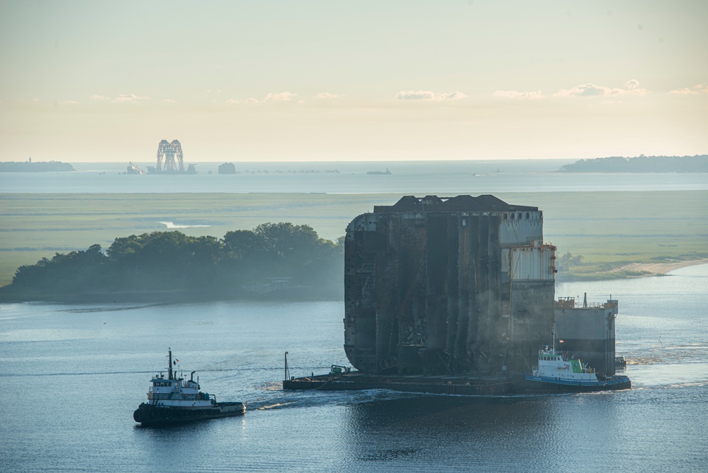 Tugs assist a dry-dock barge loaded with a section of the Golden Ray