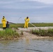 A shoreline clean-up team sprays sphagnum moss