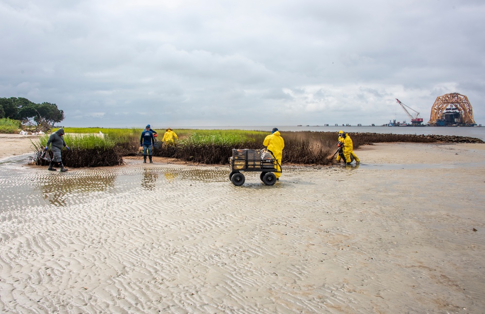 A shoreline clean-up team applies another treatment of sphagnum moss