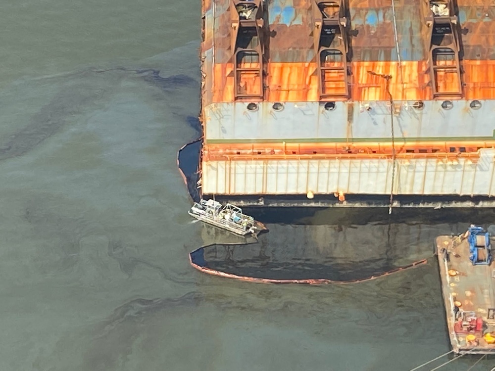 A skimmer vessel removes oil retained inside the boom