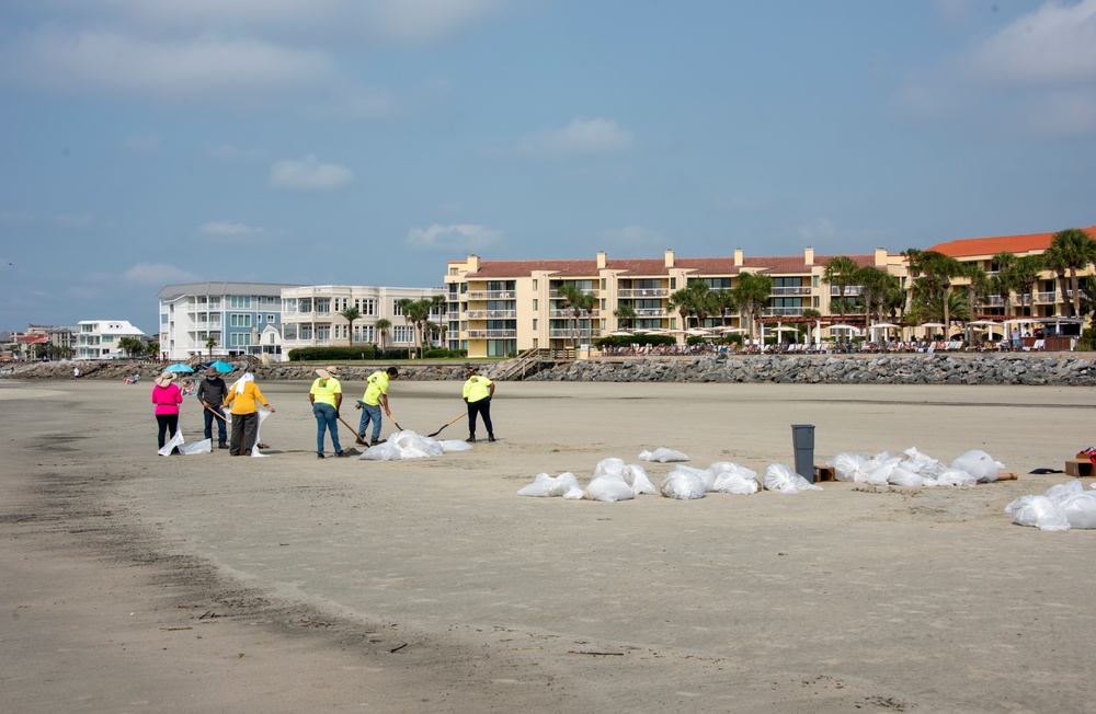 A shoreline clean-up team fills bags of oiled sand