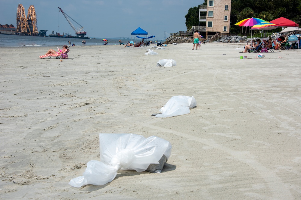 Bags of oiled sand await pickup by shoreline clean-up teams