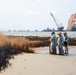 A shoreline clean-up team applies sphagnum moss to oil marsh grass