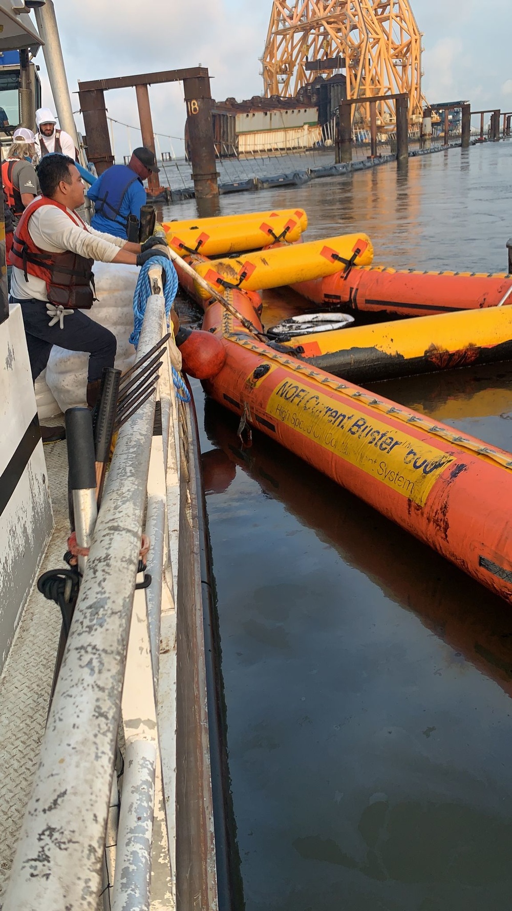 A response vessel crew removes oil from a Current Buster