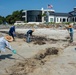 A shoreline clean-up team gathers oiled sand for removal