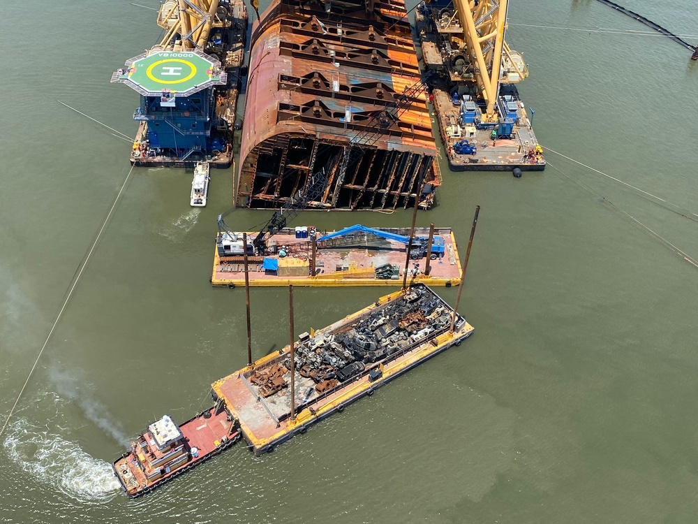 A tug removes a barge fully loaded with vehicles