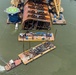 A tug removes a barge fully loaded with vehicles