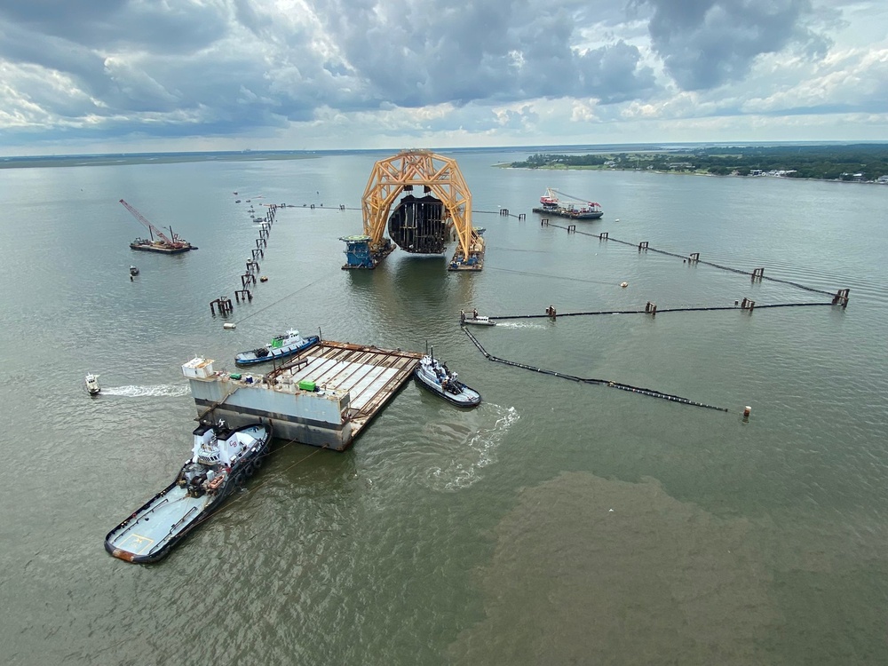 Tugs guide a dry-dock barge underneath the Golden Ray wreck