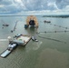 Tugs guide a dry-dock barge underneath the Golden Ray wreck