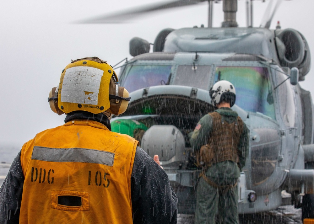 SN John Lopez Signals an MH-60R Helicopter aboard the USS Dewey