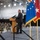 Kentucky Air Guard enters new era with arrival of C-130J Super Hercules aircraft A civilian in a dark suit is speaking at a podium during a formal military ceremony held inside what appears to be an aircraft hangar or large military facility. An audience of uniformed military personnel wearing face masks is seated in the background, suggesting this event took place during the COVID-19 pandemic. Multiple ceremonial flags, including what appears to be a U.S. Air Force flag, a general officer flag, and a Kentucky state flag, are displayed on the stage.