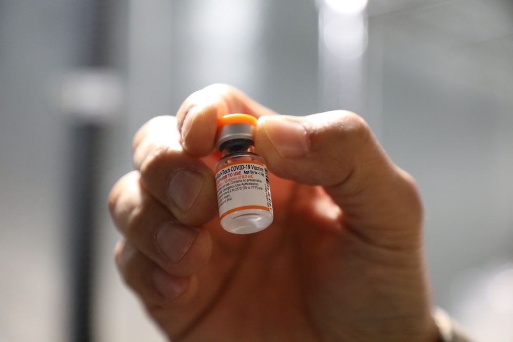 A pharmacist inspects a pediatric COVID-19 vaccine vial