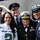 New York Jets Salute to Service Game 11/14/21 A group of five people pose together at a New York Jets NFL game, with four individuals in various U.S. military dress uniforms and one civilian wearing a New York Jets jersey. The setting appears to be at MetLife Stadium, with Jets branding visible in the background. The group appears to be participating in a military appreciation event commonly held during NFL games.