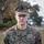 A U.S. Navy servicemember is photographed in a formal portrait-style image wearing Marine Corps MARPAT digital camouflage utilities. The name tape reads 'TABISZ' and the branch tape reads 'U.S. NAVY', indicating a Navy sailor assigned to a Marine Corps unit. The individual wears what appears to be a Fleet Marine Force (FMF) warfare device on the chest along with rank insignia.