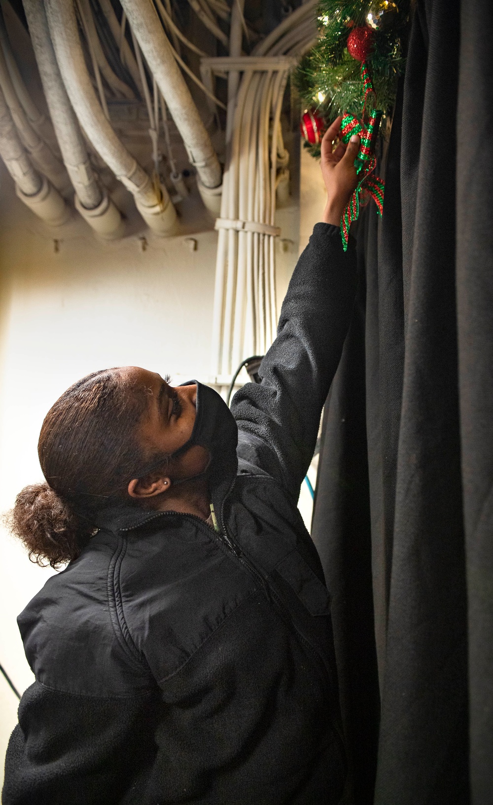 Nimitz Sailor Hangs Christmas Decoration