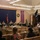 A formal military panel discussion or town hall meeting is taking place at an Army Hawaii facility, with approximately five uniformed personnel seated at a table on a stage facing an audience. The setting appears to be a chapel or auditorium decorated for the Christmas holiday season, with wreaths, small Christmas trees, and an Advent banner visible. A Brigadier General's flag (one star) and a unit guidon are displayed on stage.