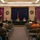 A U.S. Army panel discussion or town hall meeting is being held in what appears to be a military chapel decorated for the Christmas season. Several uniformed military personnel and at least one civilian are seated at a long table with U.S. Army branded signage, facing an audience of soldiers and civilians seated in rows of chairs. A general officer's flag (brigadier general star pennant) is visible centered behind the panel table.