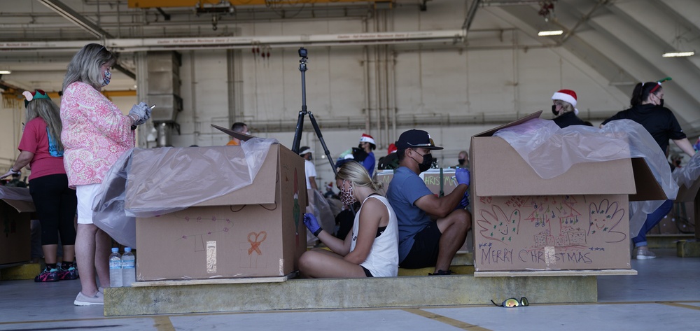 Volunteers pack donated goods into airdrop bundles during the 70th annual Operation Christmas Drop