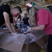 Volunteers pack donated goods into airdrop bundles during the 70th annual Operation Christmas Drop