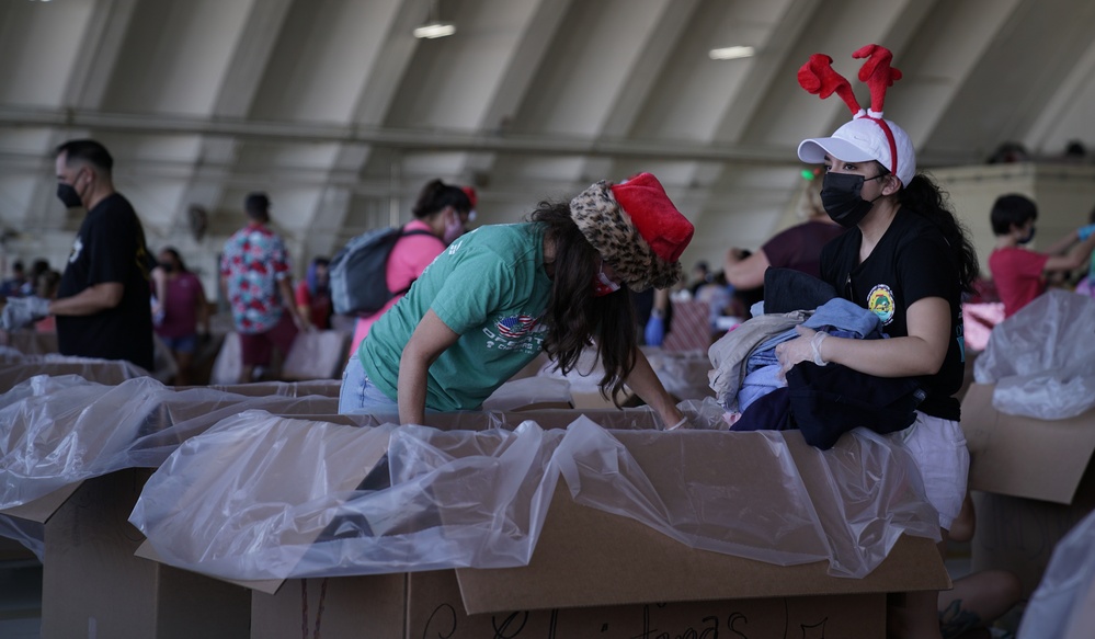 Volunteers pack donated goods into airdrop bundles during the 70th annual Operation Christmas Drop