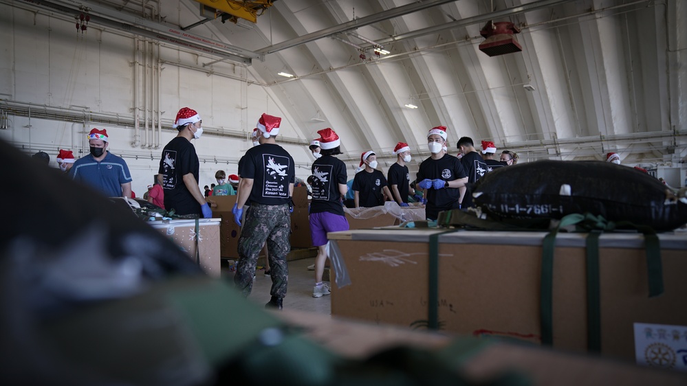 Volunteers pack donated goods into airdrop bundles during the 70th annual Operation Christmas Drop