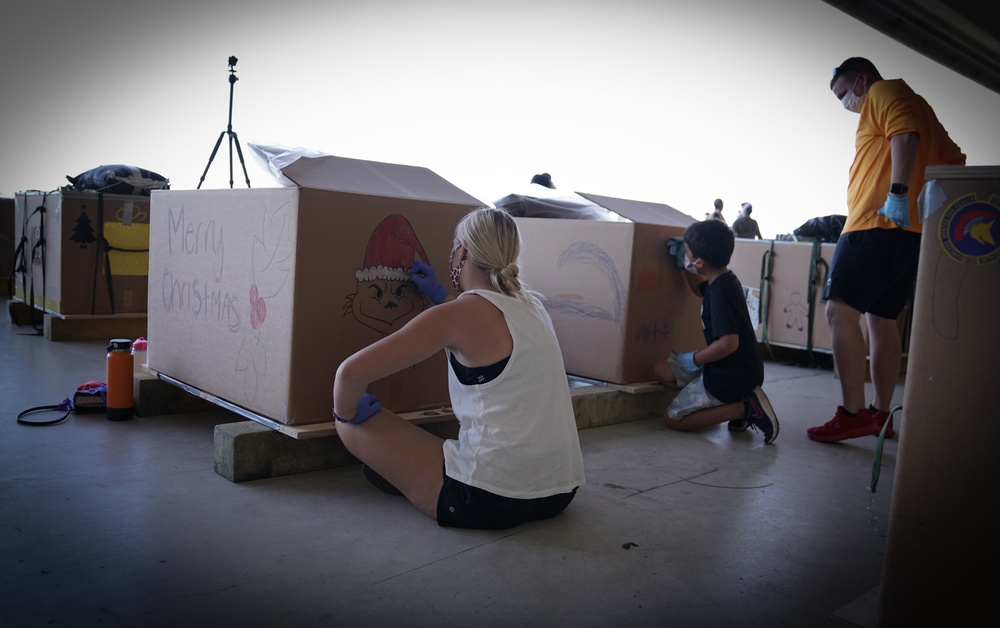 Volunteers pack donated goods into airdrop bundles during the 70th annual Operation Christmas Drop