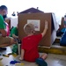 Volunteers pack donated goods into airdrop bundles during the 70th annual Operation Christmas Drop