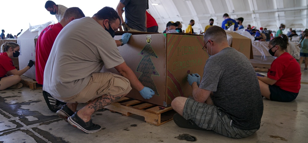 Volunteers pack donated goods into airdrop bundles during the 70th annual Operation Christmas Drop