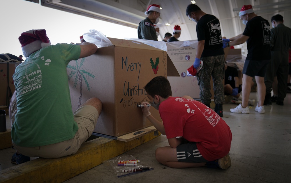 Volunteers pack donated goods into airdrop bundles during the 70th annual Operation Christmas Drop