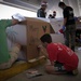 Volunteers pack donated goods into airdrop bundles during the 70th annual Operation Christmas Drop