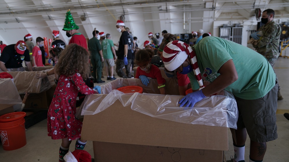 Volunteers pack donated goods into airdrop bundles during the 70th annual Operation Christmas Drop