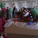 Volunteers pack donated goods into airdrop bundles during the 70th annual Operation Christmas Drop