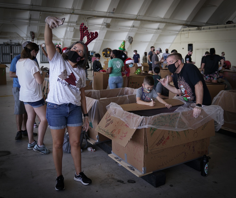 Volunteers pack donated goods into airdrop bundles during the 70th annual Operation Christmas Drop